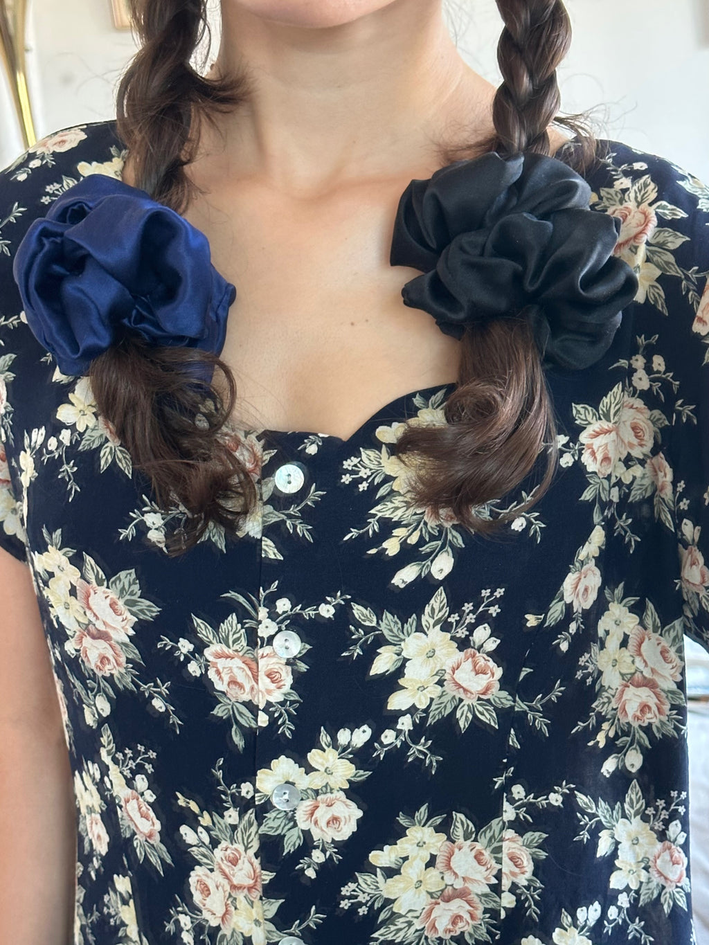 Person wearing a navy floral dress with braided hair tied with silk scrunchies