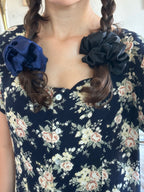 Person wearing a navy floral dress with braided hair tied with silk scrunchies